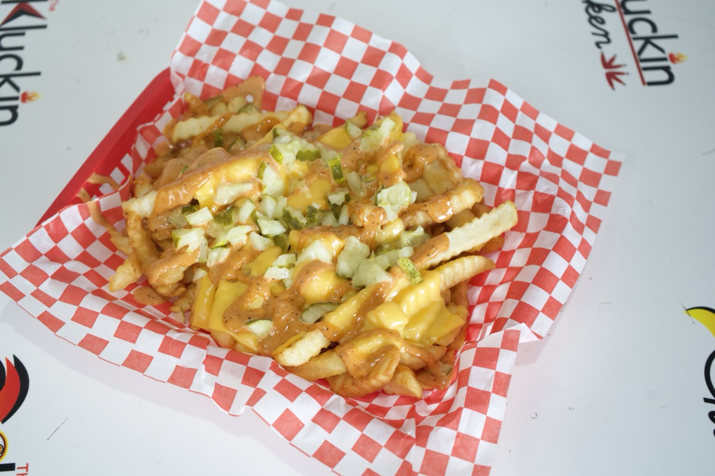 Loaded fries on checkered paper at The Kluckin Chicken, photographed in the kitchen