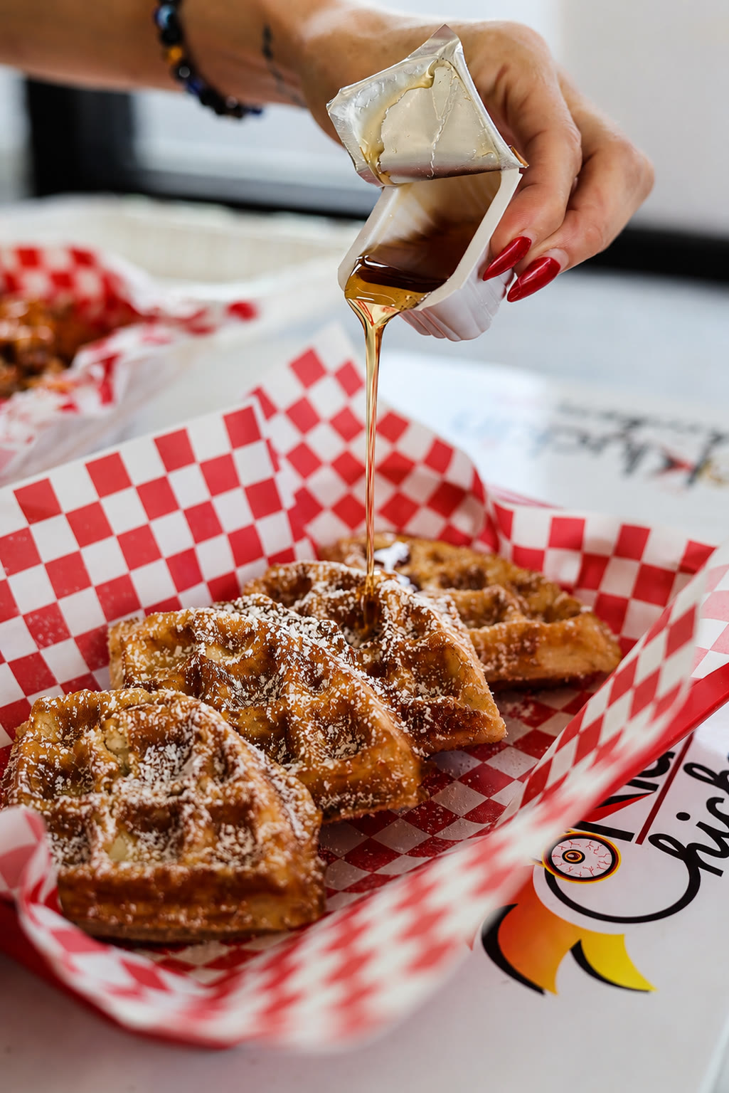 Syrup poured over Kluckin chicken and waffles